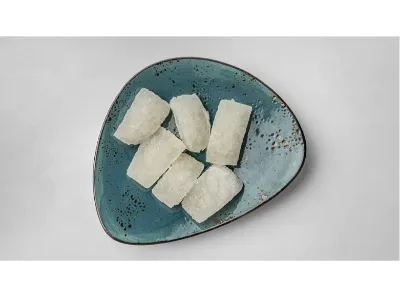 Traditional Agra plain petha pieces placed on a blue ceramic plate, showcasing the translucent sweet delicacy.