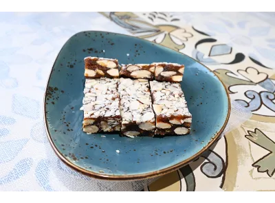 Sugarless Almond Dates Barfi topped with sliced almonds, featuring a rich and chewy texture, served in rectangular pieces.
