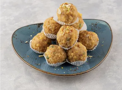 Traditional besan laddus arranged on a blue plate, garnished with dry fruits, ready to serve on festive occasions.