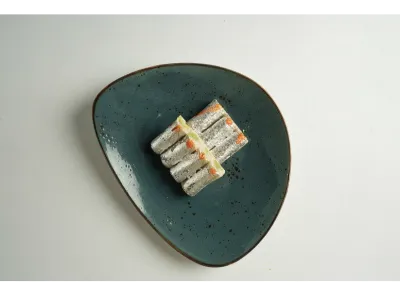 Kaju Pista Rolls topped with silver leaf and orange garnish