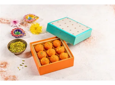 Box of Kanpuri laddus with festive decor, diyas, and dry fruits, perfect for Diwali celebrations.