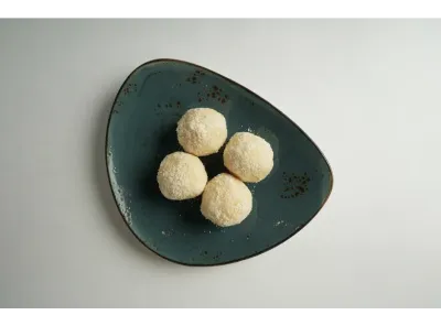 Four Kheer Kadam sweets served on a dark green triangular plate against a plain white background