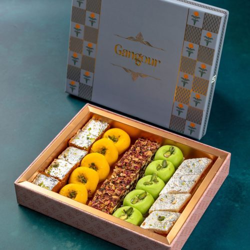 Elegant box of assorted Indian sweets including barfi, peda, and dry fruit rolls, beautifully arranged in a festive gift box