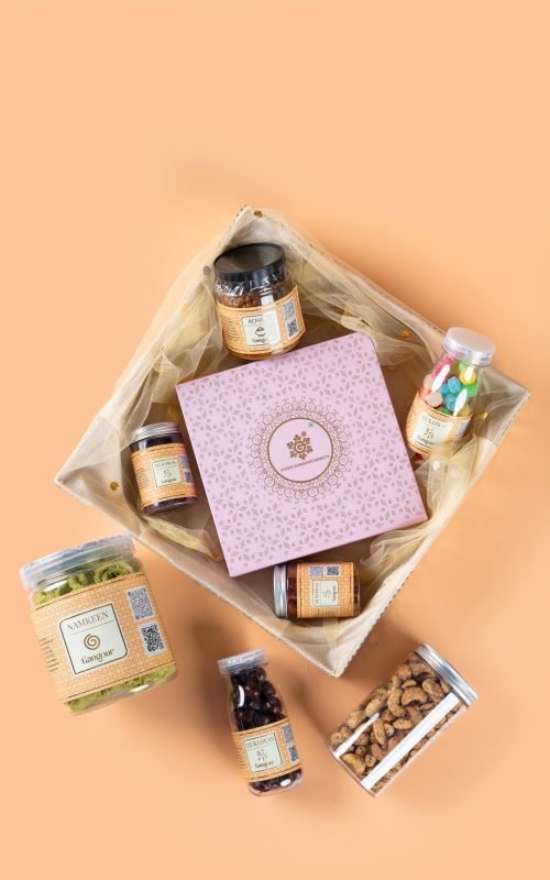 Gangour net tray hamper with assorted snacks, sweets jars, and a decorative gift box.