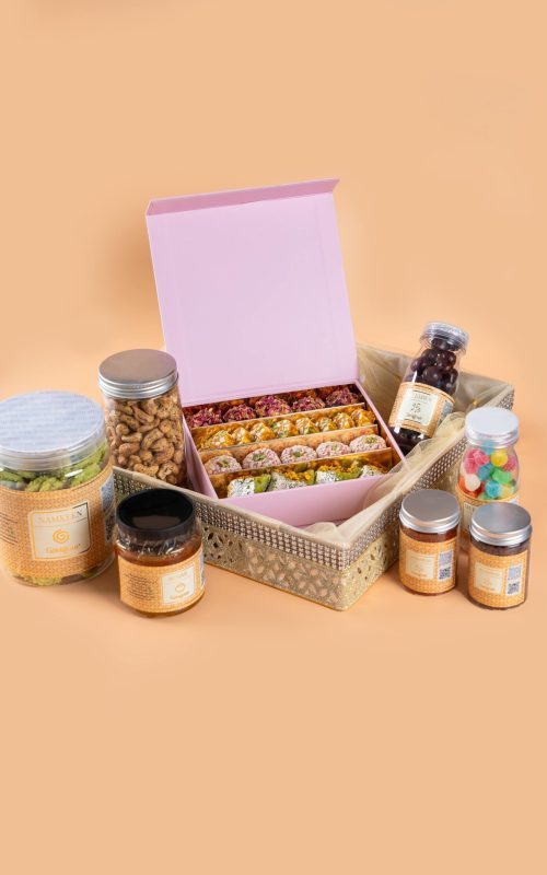 Gangour net tray hamper with assorted snacks, sweets jars, and a decorative gift box.
